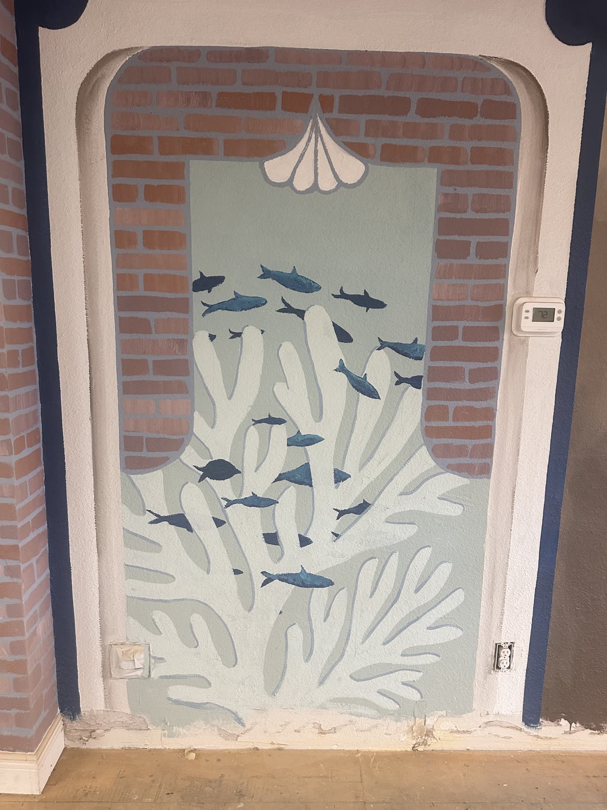 Coral and fish mural detail painted beside the brick